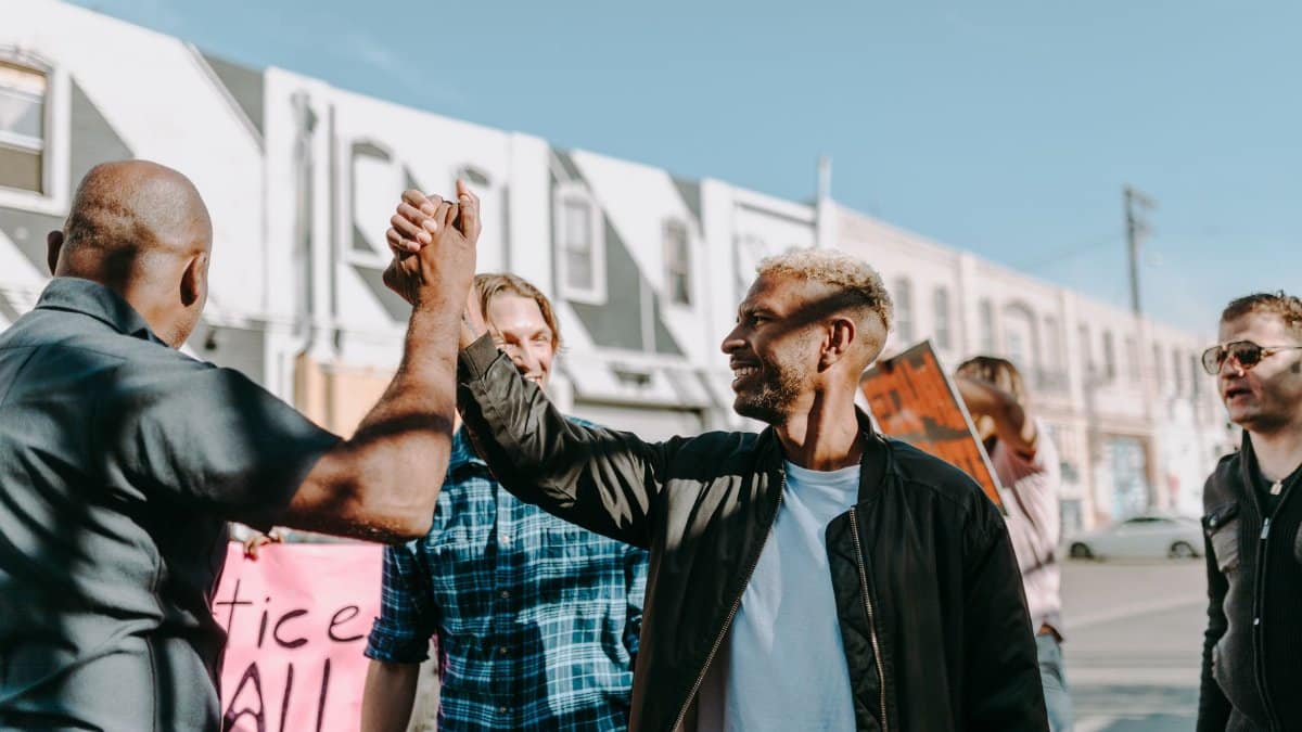 A diverse group of protesters in a street demonstration sharing a high-five moment.
