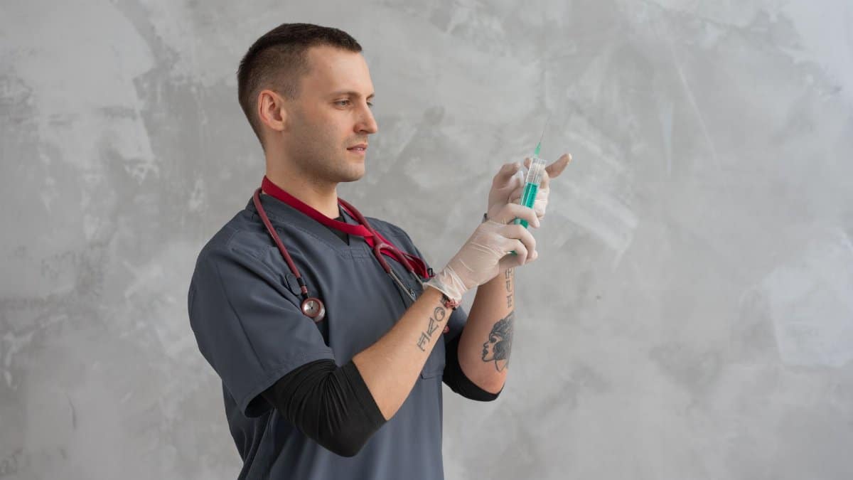 Male healthcare worker preparing syringe with focus and precision.