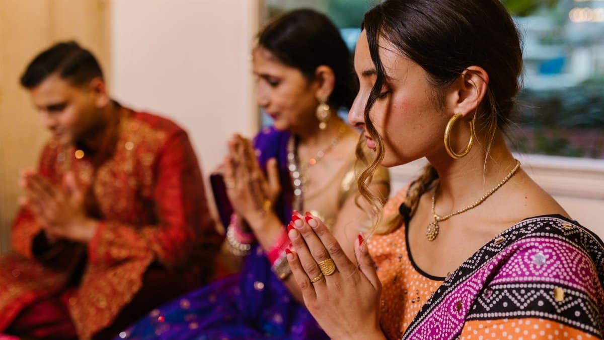 Indian family engaged in a traditional prayer ceremony, wearing vibrant ethnic attire.