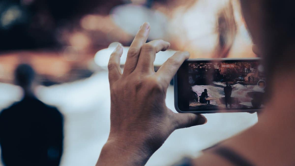 A person photographs an urban scene with a smartphone, capturing street life.