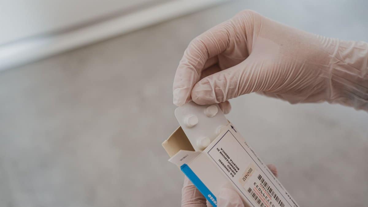 Close-up of hands in gloves handling medication blister pack, ensuring safety and hygiene in healthcare.