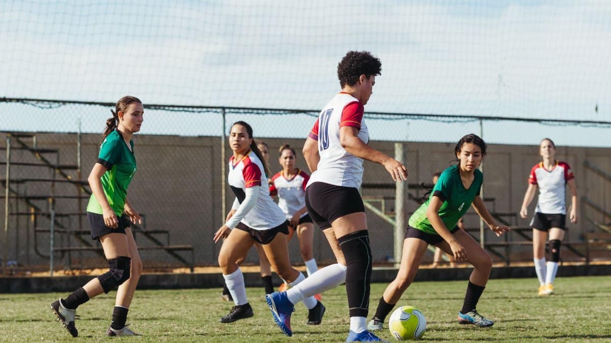 Women soccer players in intense action during a sunny outdoor match, showcasing teamwork and athletic skills.