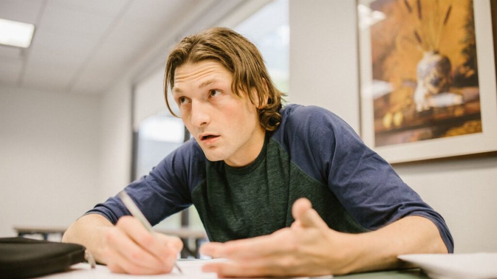 A college student intently focusing on a test in a classroom environment.
