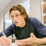 A college student intently focusing on a test in a classroom environment.