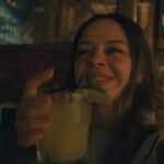 A cheerful woman savoring a cocktail in a cozy San Francisco bar, embracing the night ambiance.