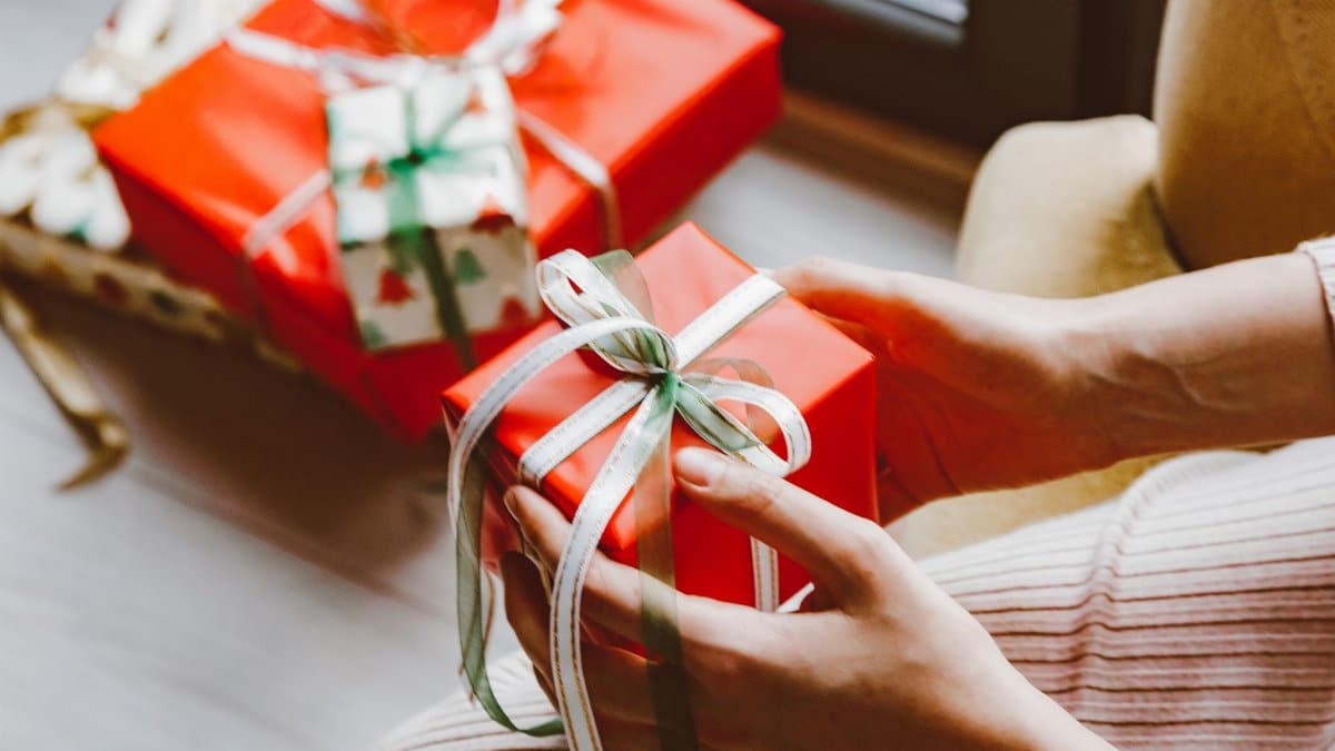 Close-up of hands holding a wrapped Christmas gift tied with ribbon, capturing the festive mood.