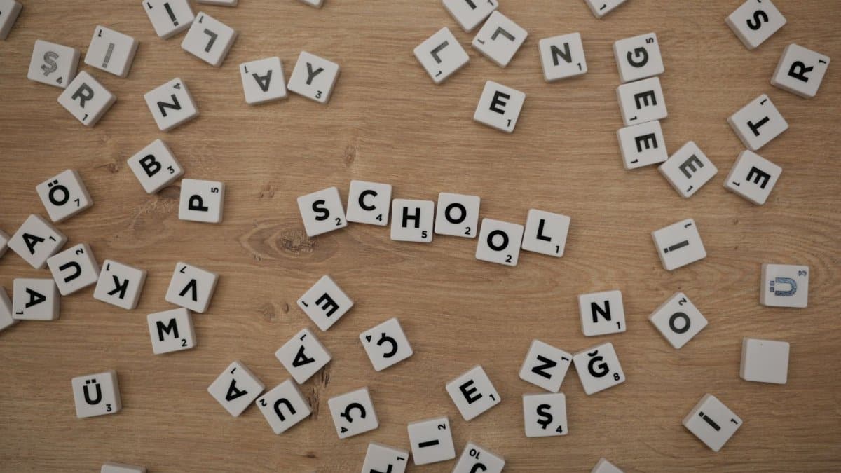 Scattered Scrabble tiles on wood with 'School' spelled out, ideal for educational themes.