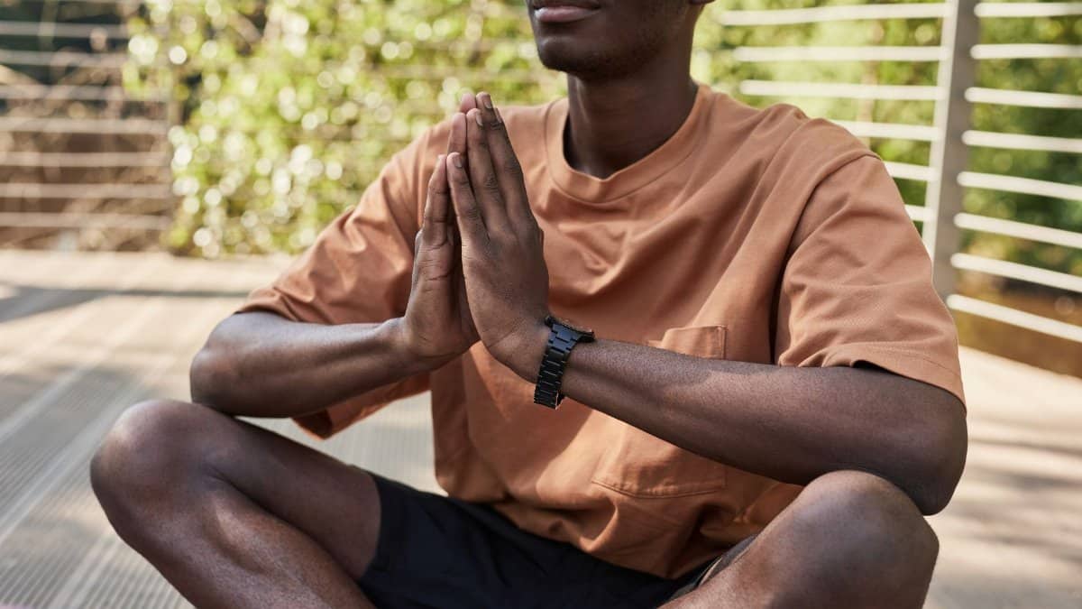 Man practicing yoga outdoors, sitting cross-legged in meditation pose.