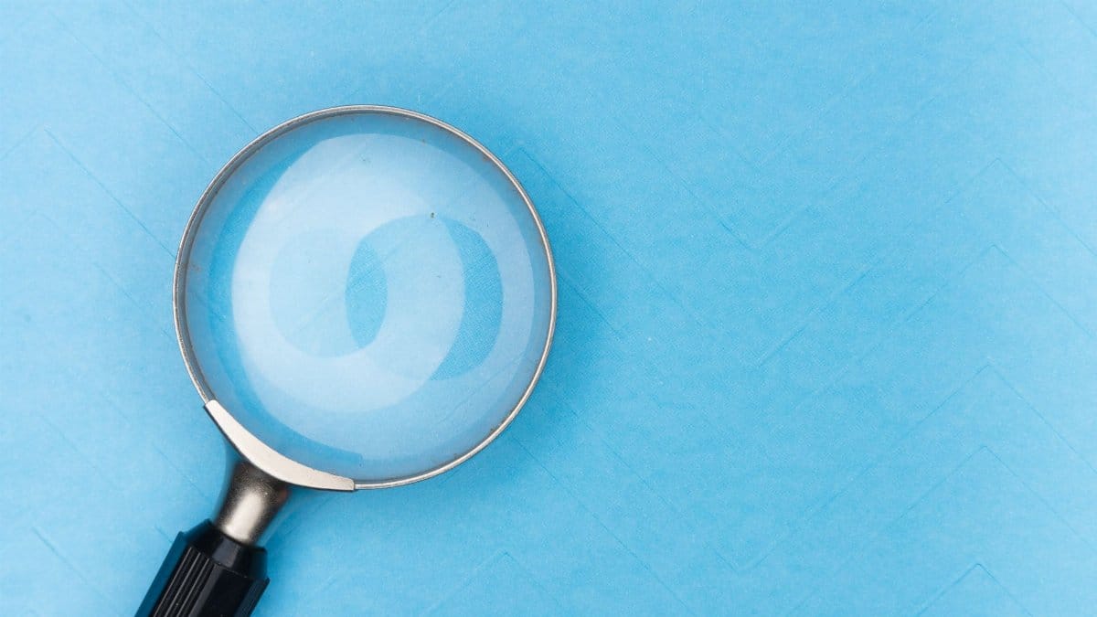 Close-up of a magnifying glass on a blue surface, ideal for search and exploration themes.