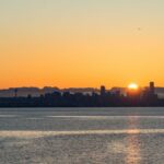 Breathtaking view of Seattle skyline at sunset with vibrant orange hues over calm waters.