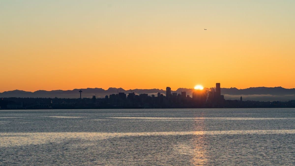 Breathtaking view of Seattle skyline at sunset with vibrant orange hues over calm waters.