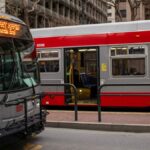 Red and gray buses at a bustling San Francisco downtown bus stop.
