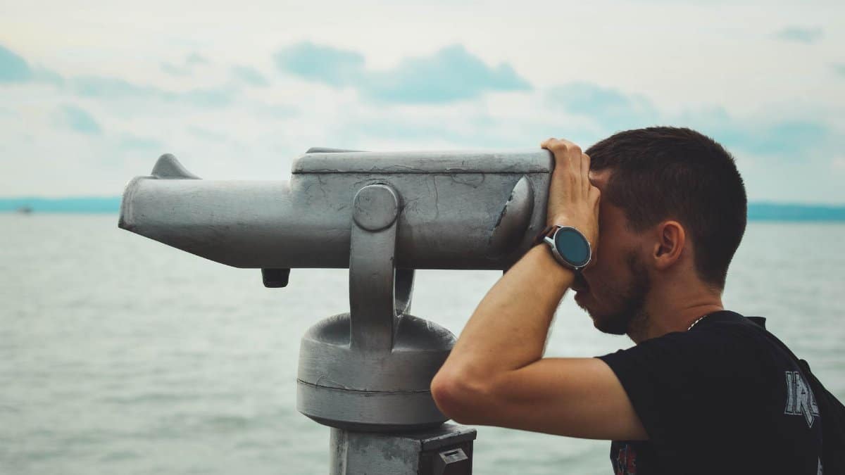 A man looks through binoculars over Lake Balaton in Siófok, Hungary, during the day.