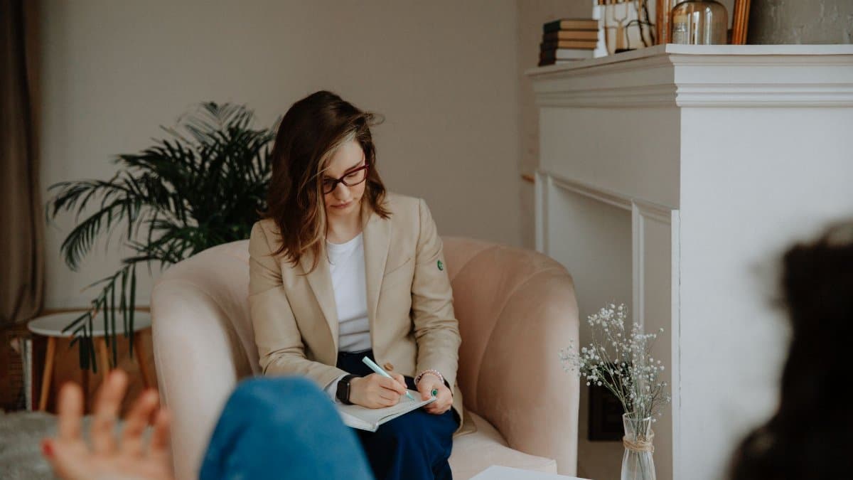 A professional therapist takes notes during a private counseling session in a cozy room.