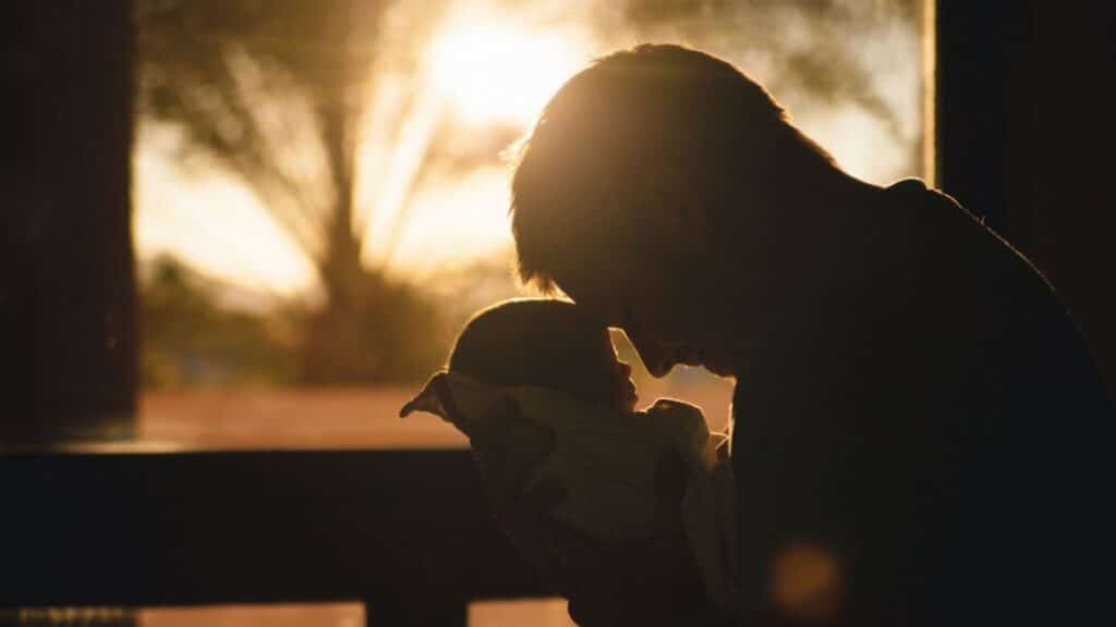 Silhouette of a father holding his newborn at sunset, highlighting love and connection.