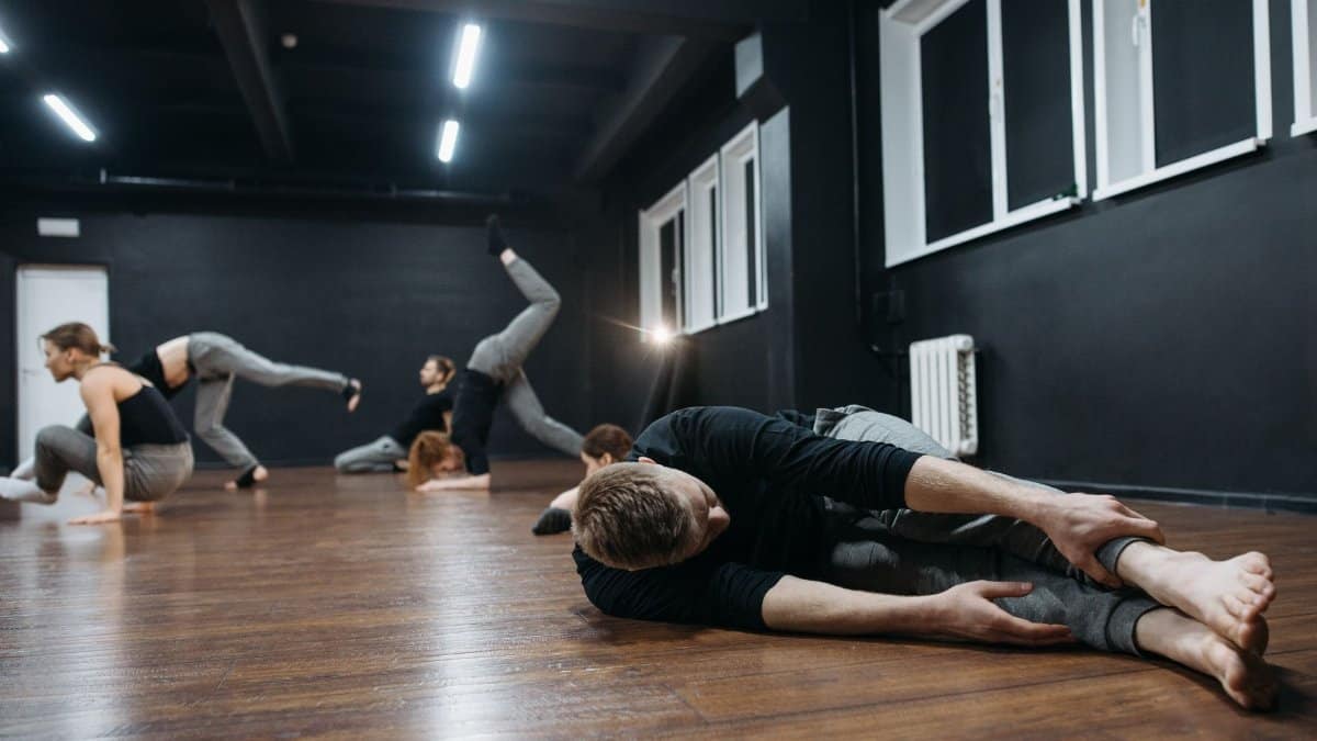 Group of dancers practicing in a modern dance studio, showcasing flexibility and movement.