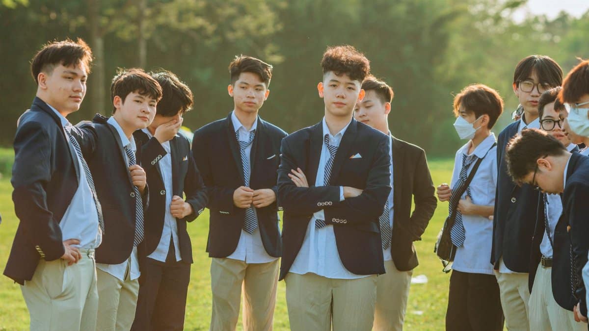 A group of young men wearing suits and ties, standing outdoors in a grassy field.