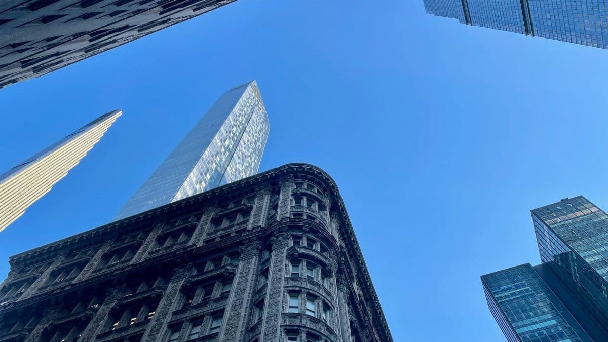 Low angle view of New York City skyscrapers against a clear blue sky, capturing urban architecture.