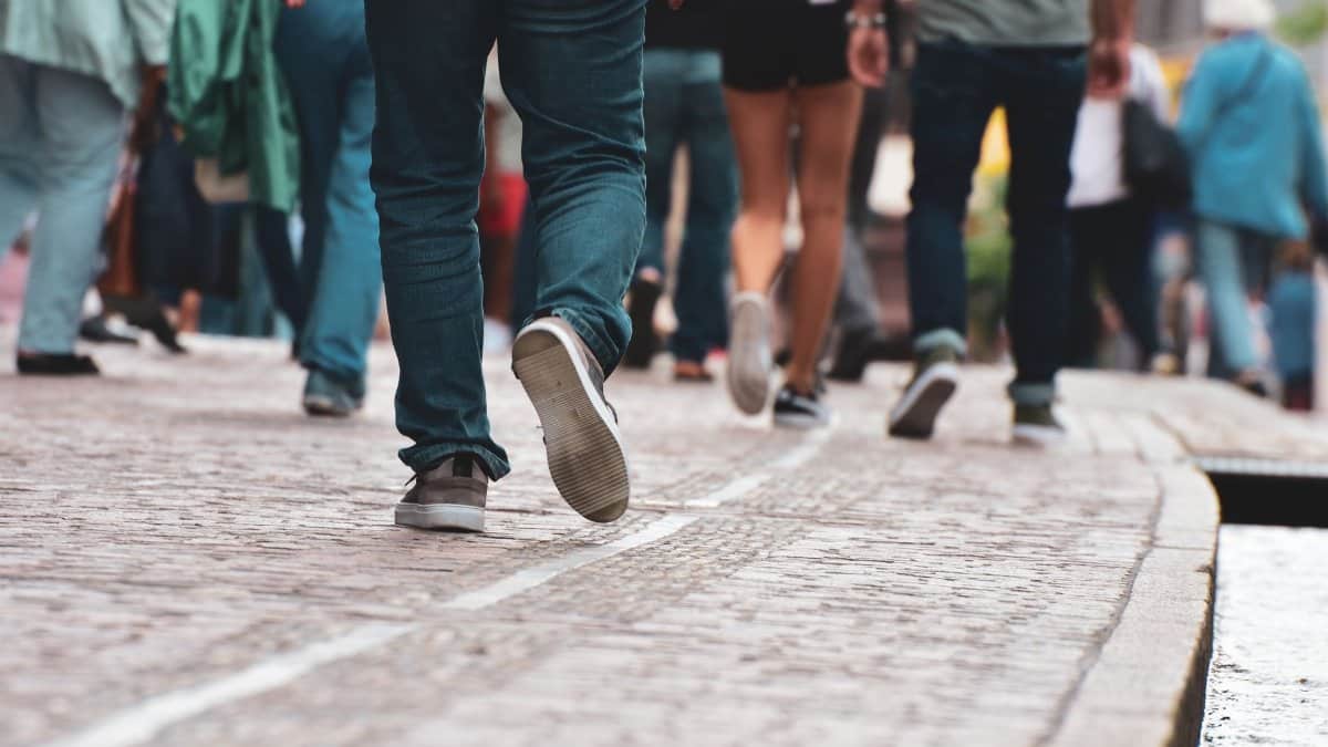 A diverse group of individuals walking on a cobblestone street, showcasing urban daily life.