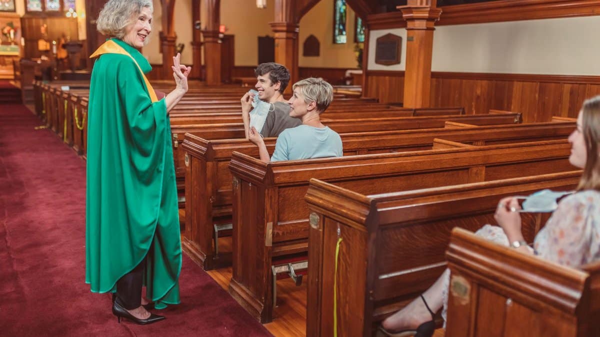 A priest interacts with parishioners inside a church, emphasizing community spirit.