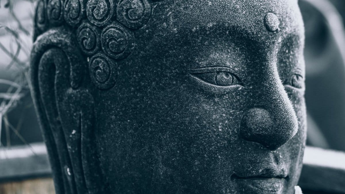 Detailed close-up of a Buddha statue covered in frost, conveying spiritual serenity in winter.
