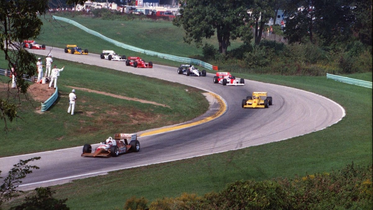 High-speed race cars on a curving track at Elkhart Lake, capturing motorsport excitement.