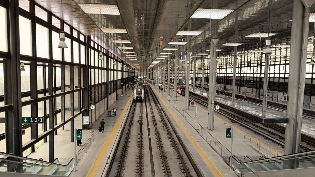 A bustling train station in Cádiz with modern architecture and multiple tracks.