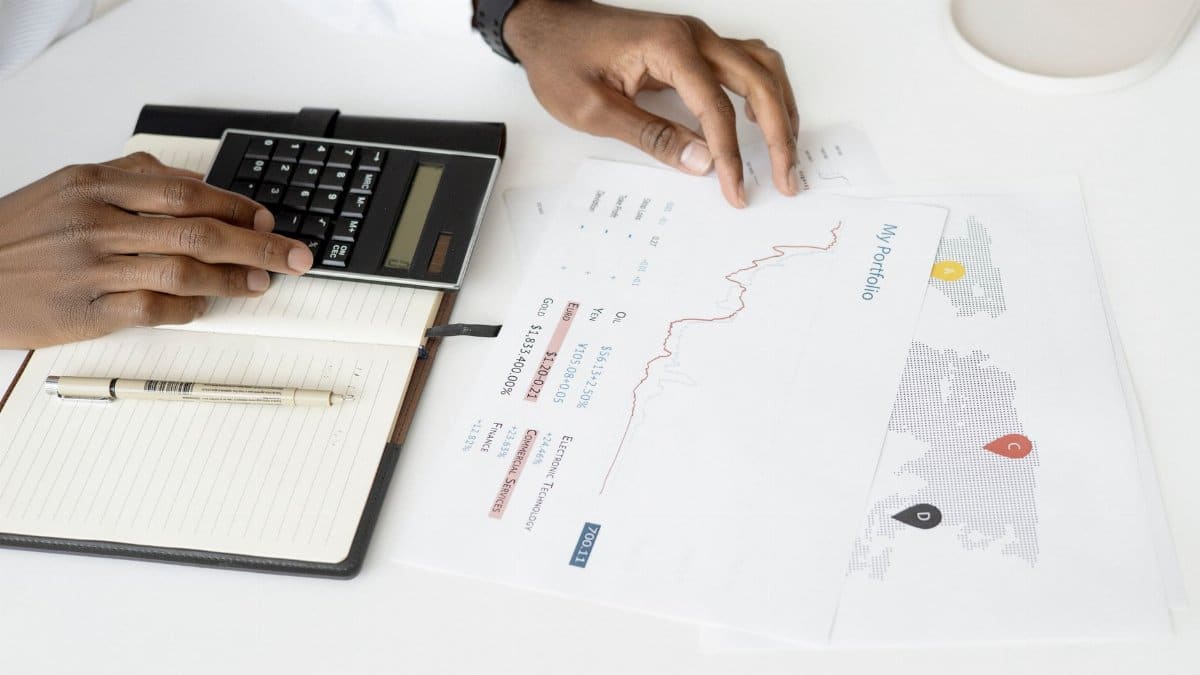 Overhead view of a person analyzing financial documents using a calculator for investment planning.