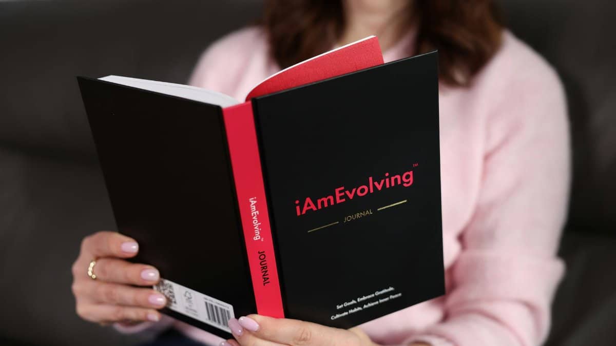Woman reading the 'iAmEvolving' journal at home. Perfect for themes of personal growth and mindfulness.