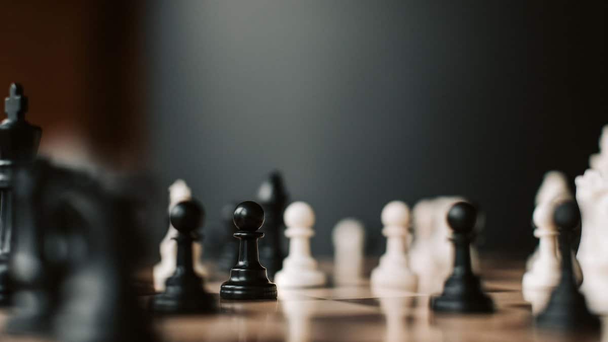 Close-up of black and white chess pieces on a chessboard, highlighting strategic gameplay.