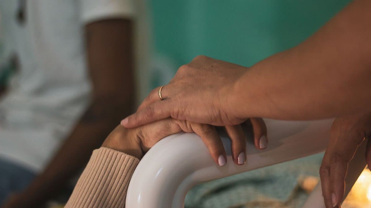 Close-up of comforting hands touching in a hospital room, symbolizing support and compassion.
