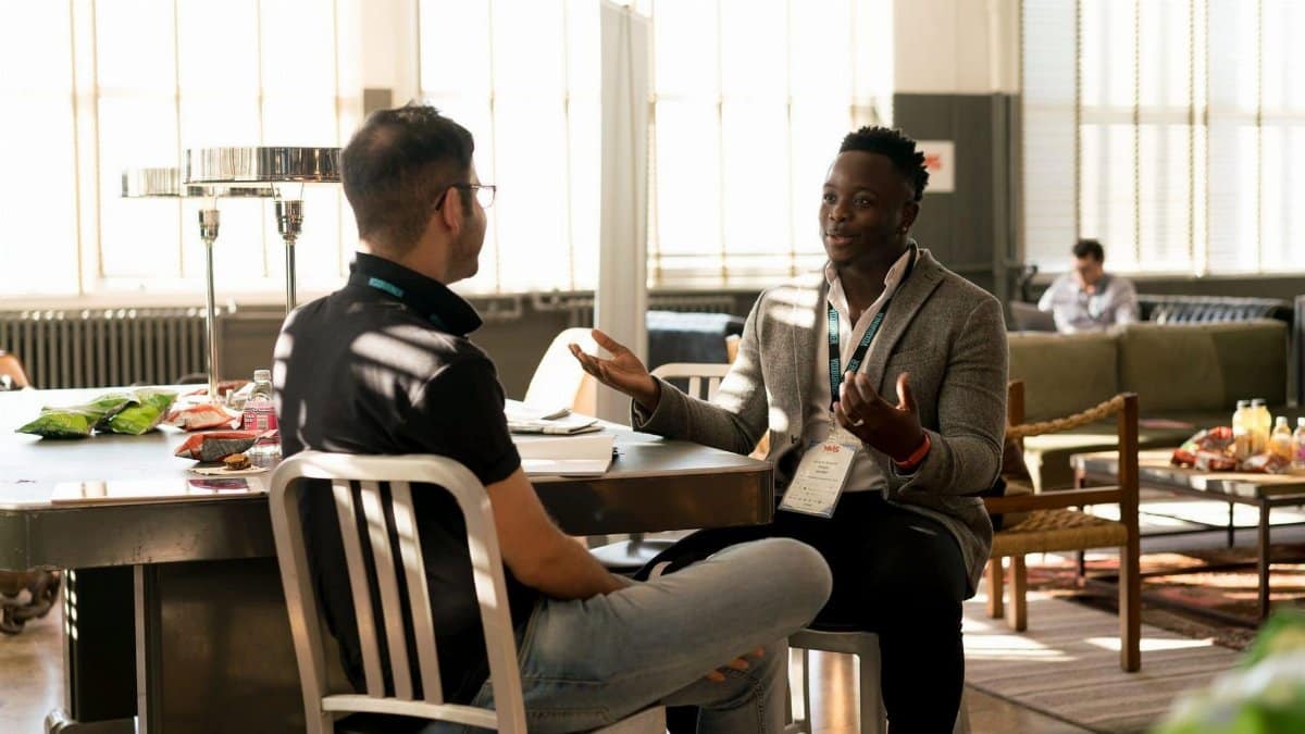 Two men having a casual discussion in a bright indoor setting, highlighting mentorship.