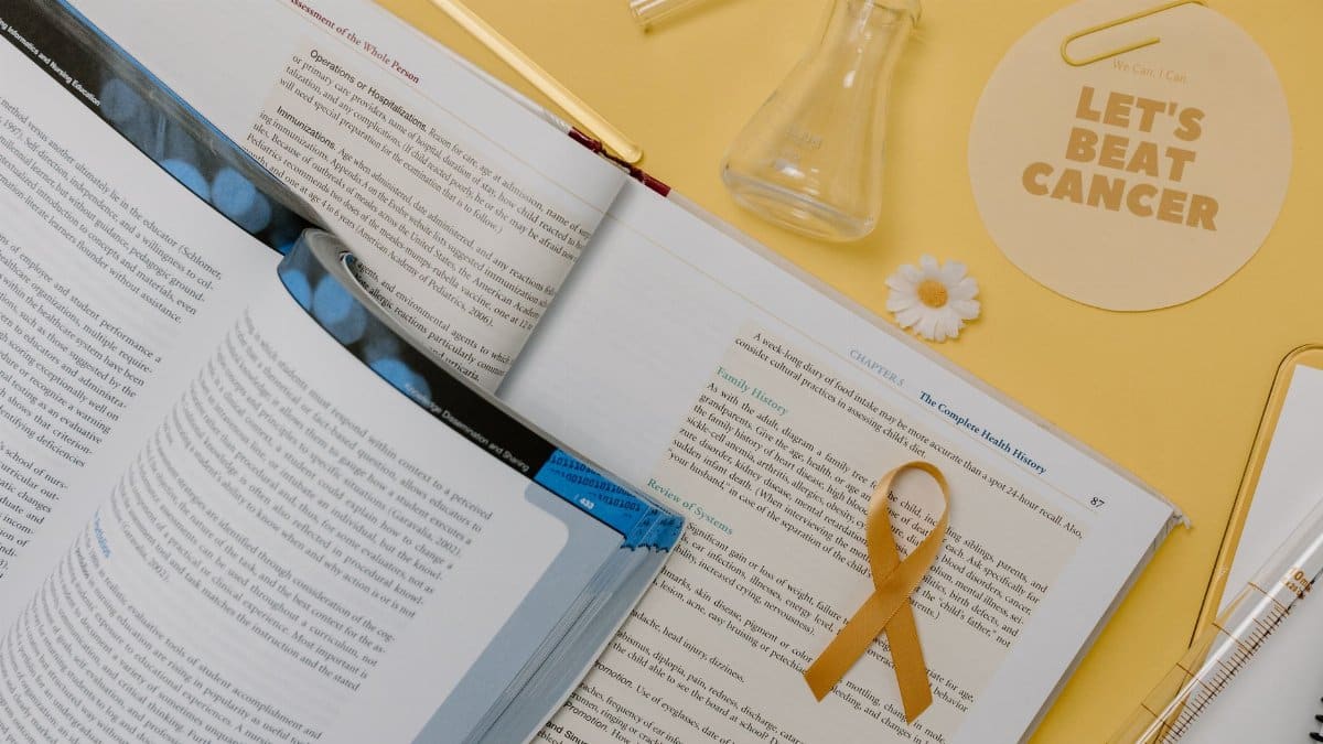 Flat lay of scientific research tools and gold ribbon for cancer awareness.