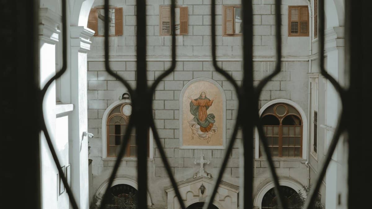 View of St. Mary Draperis Church courtyard through iron bars in Istanbul.