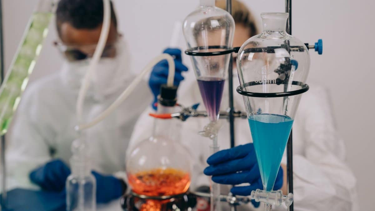 Scientists in protective gear conducting chemical experiments in a lab environment.