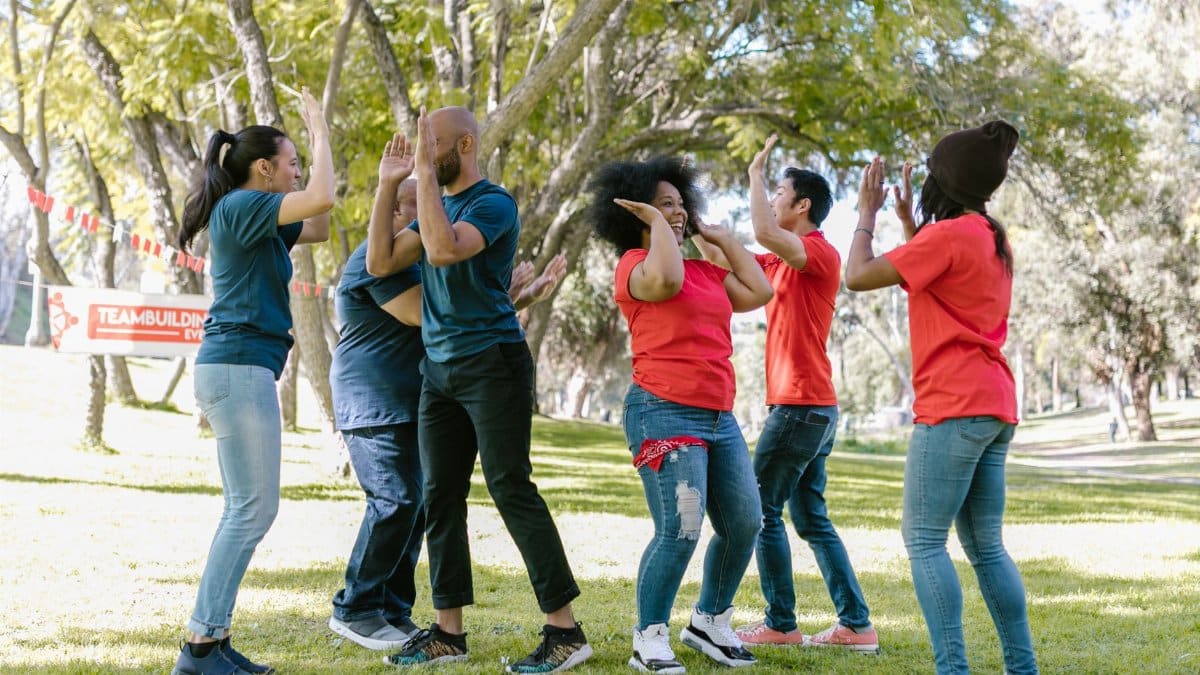 Diverse group of adults enjoying an energetic team building activity in a sunny park.