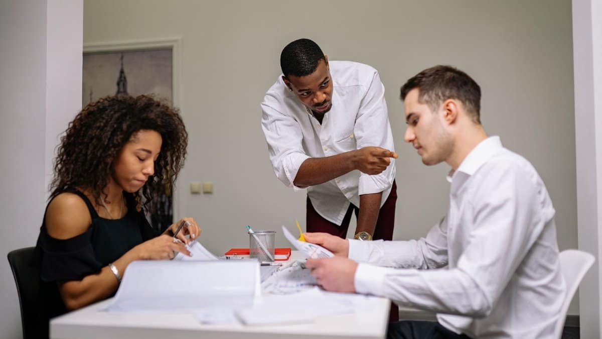 Manager instructing employees during a focused team meeting in a modern office setting.