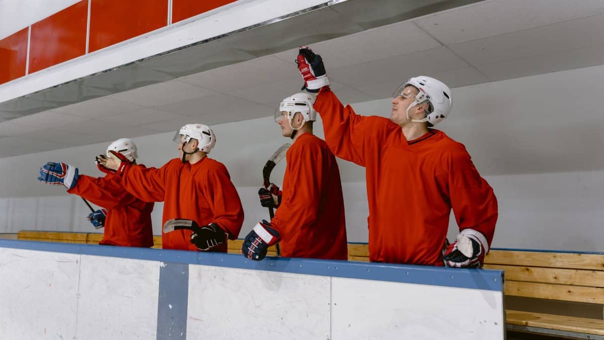Team of ice hockey players in red uniforms cheering at the rink.