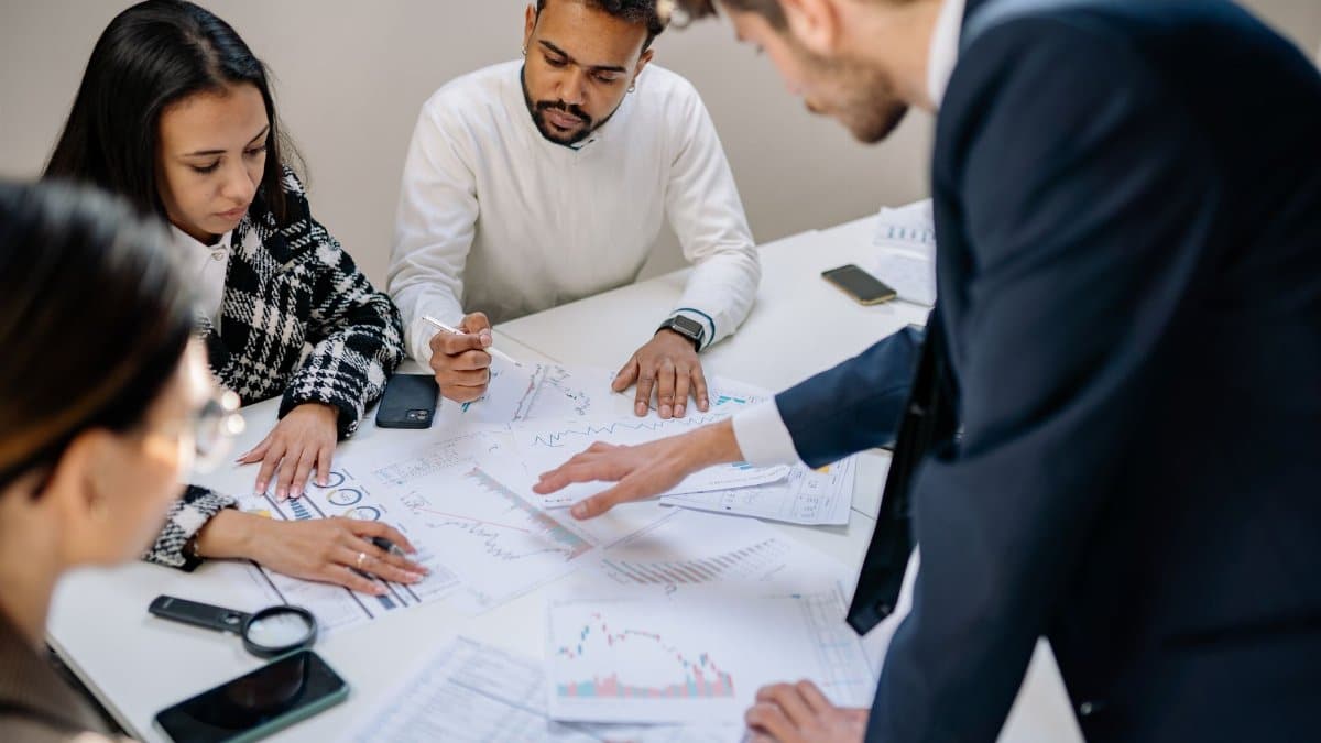 A diverse team collaborating in an office meeting, discussing papers with charts.