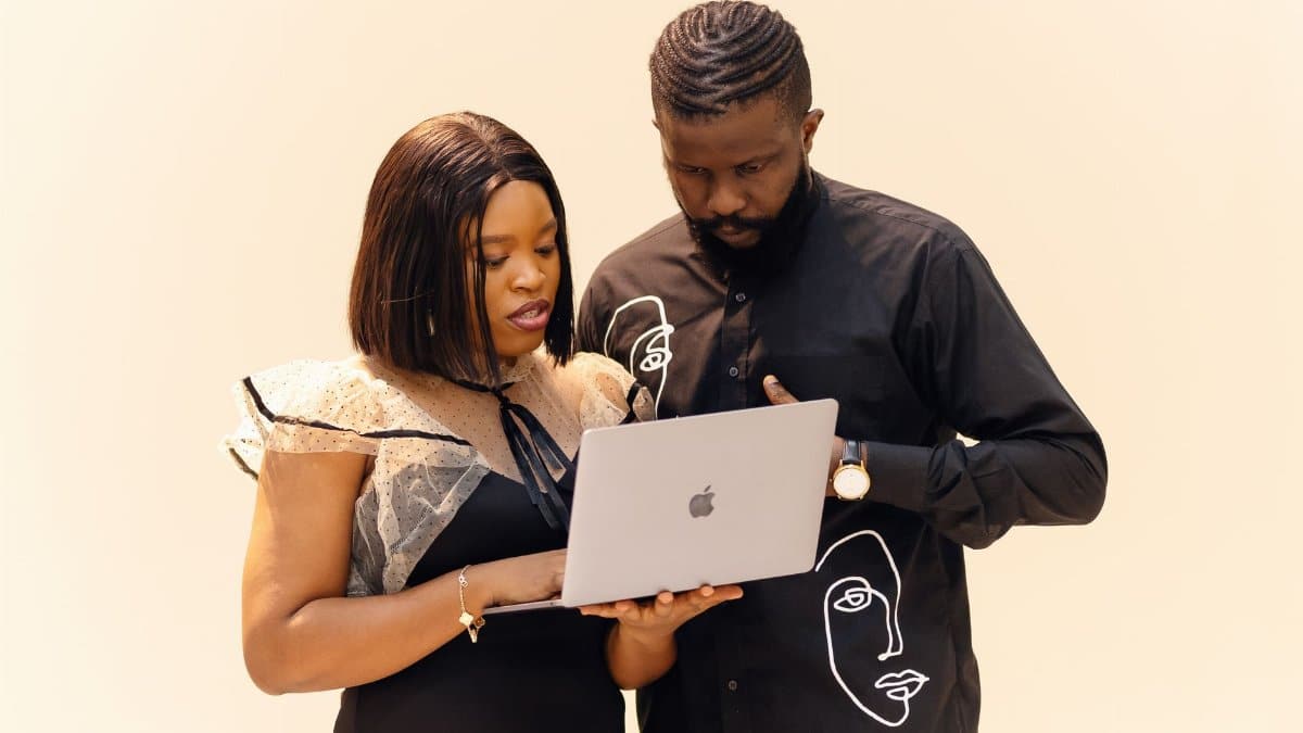 Two professionals working together on a laptop, showcasing teamwork in a modern office setting.