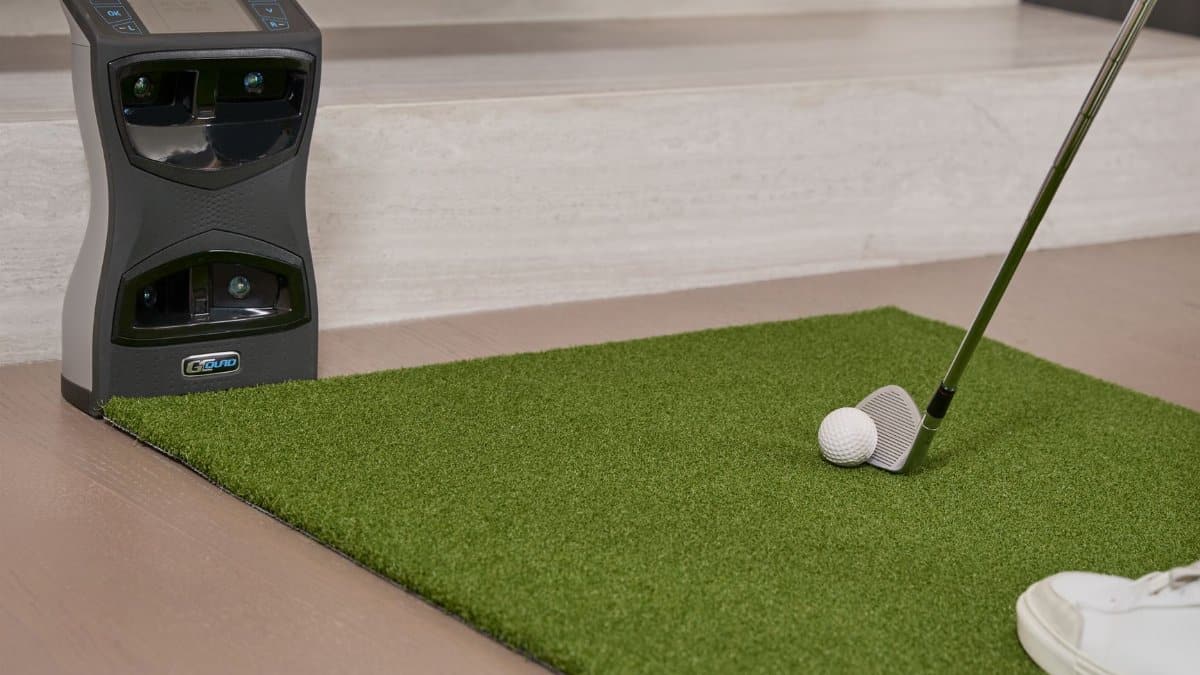 Golf putting practice on artificial turf with a training aid indoors.