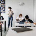 Students and teacher in a classroom wearing masks, embracing new normal education setting.