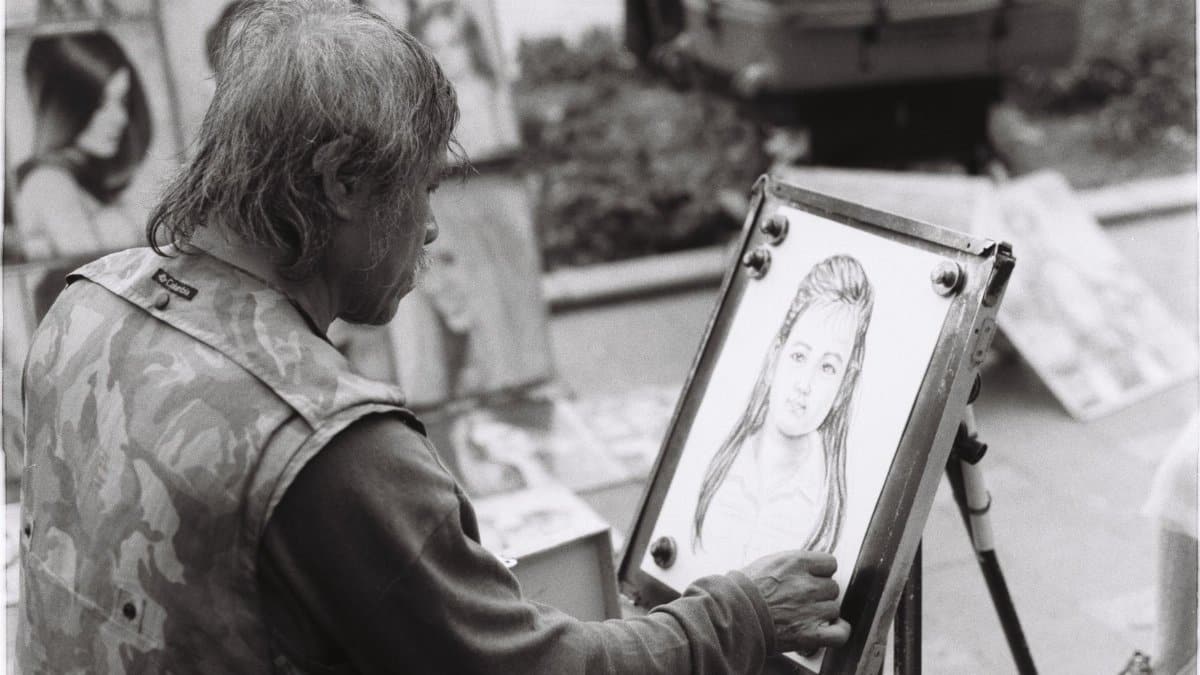 Street artist drawing a portrait in black and white with focus on talent and creativity.