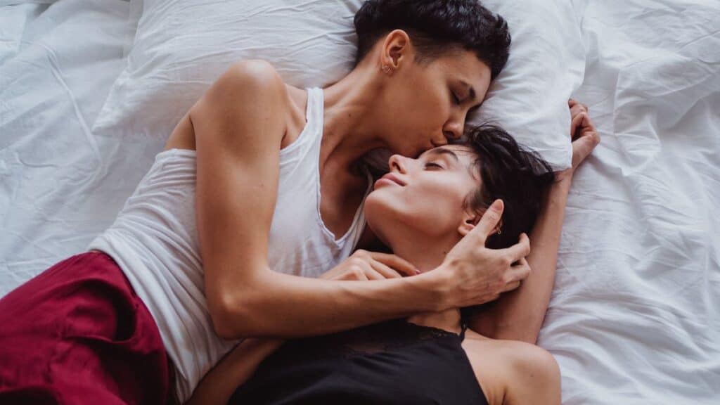 A romantic scene of a same-sex couple embracing in a peaceful, intimate setting at home.