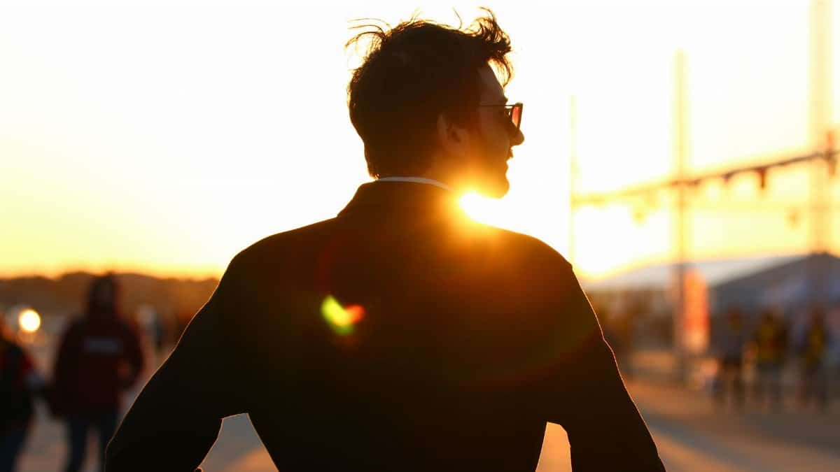 Silhouette of a man with sunglasses at sunset, featuring a warm lens flare.