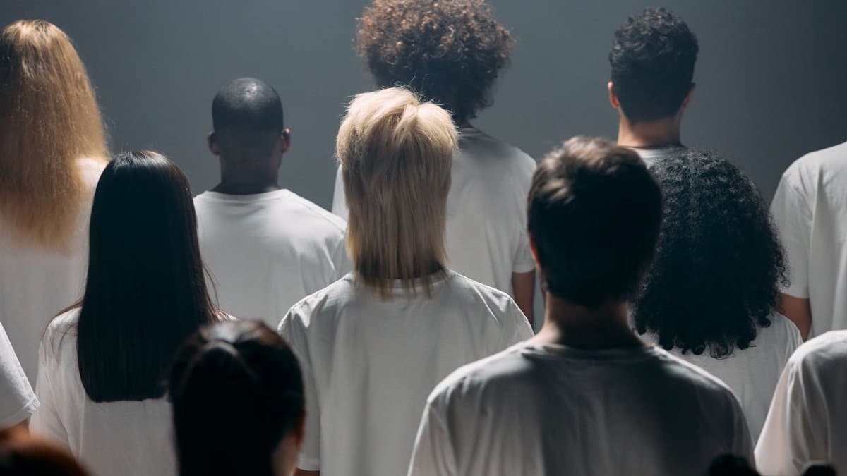 A diverse group of people seen from behind in a studio setting, emphasizing individuality and unity.