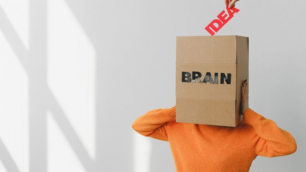 Faceless person putting Idea title in carton container with Brain inscription on head of female against wall with shadow