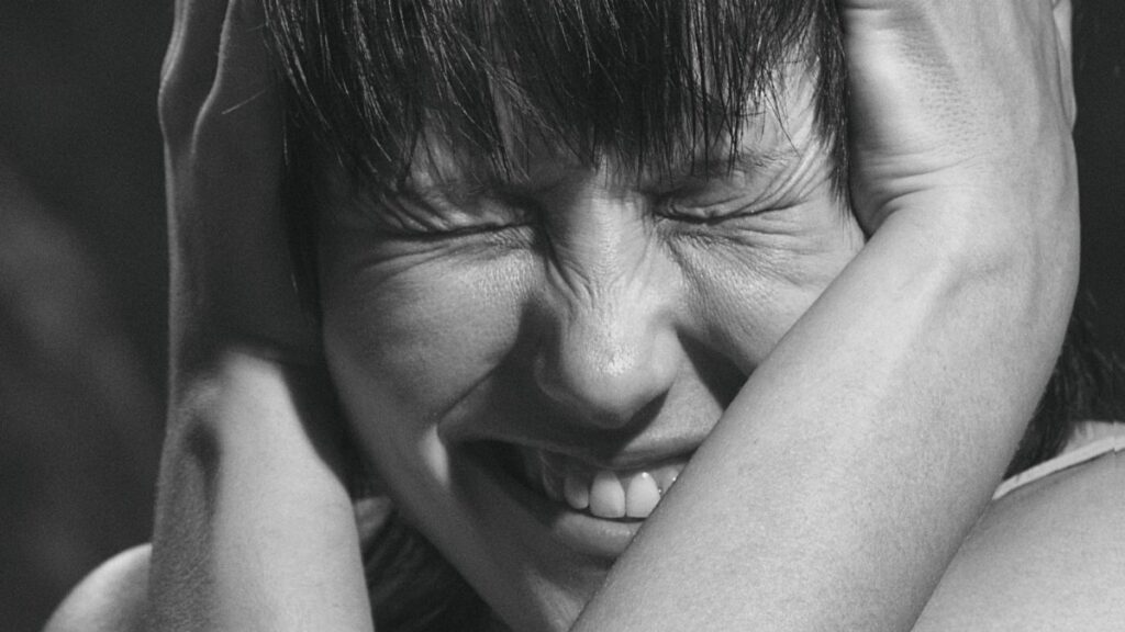 Emotional black and white close-up portrait of a woman expressing pain and frustration.