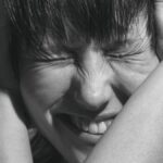Emotional black and white close-up portrait of a woman expressing pain and frustration.