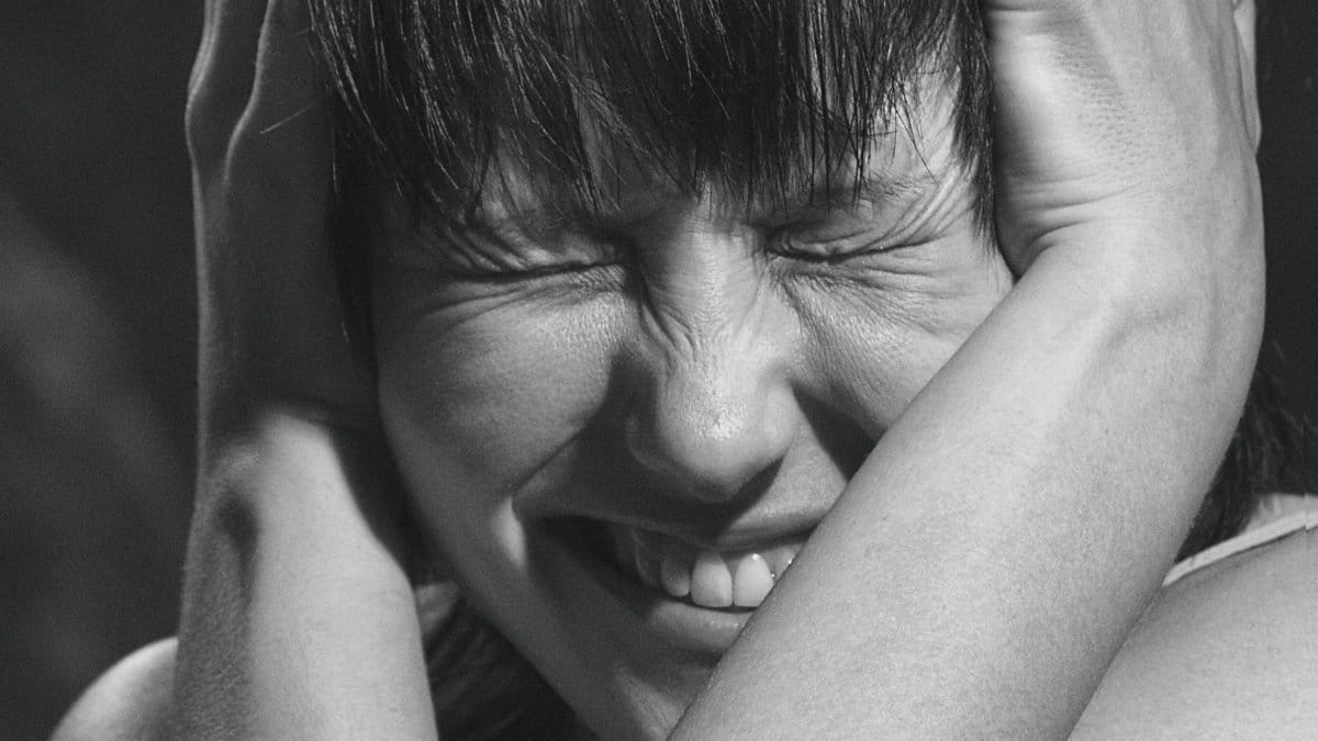Emotional black and white close-up portrait of a woman expressing pain and frustration.